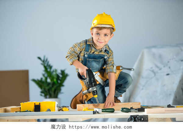 可爱的小男孩在玩玩具钻木器工具的小男孩 